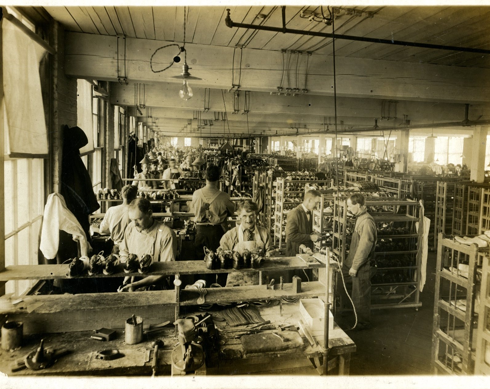 Workers at benches inside the shoe factory, about 1920